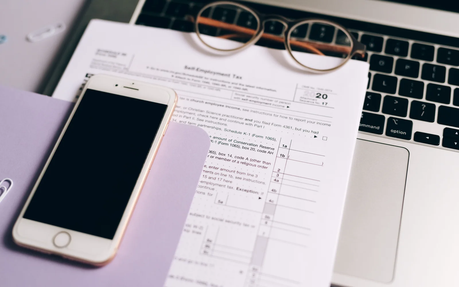 Documents, phone and laptop arranged on a desk during application prep
